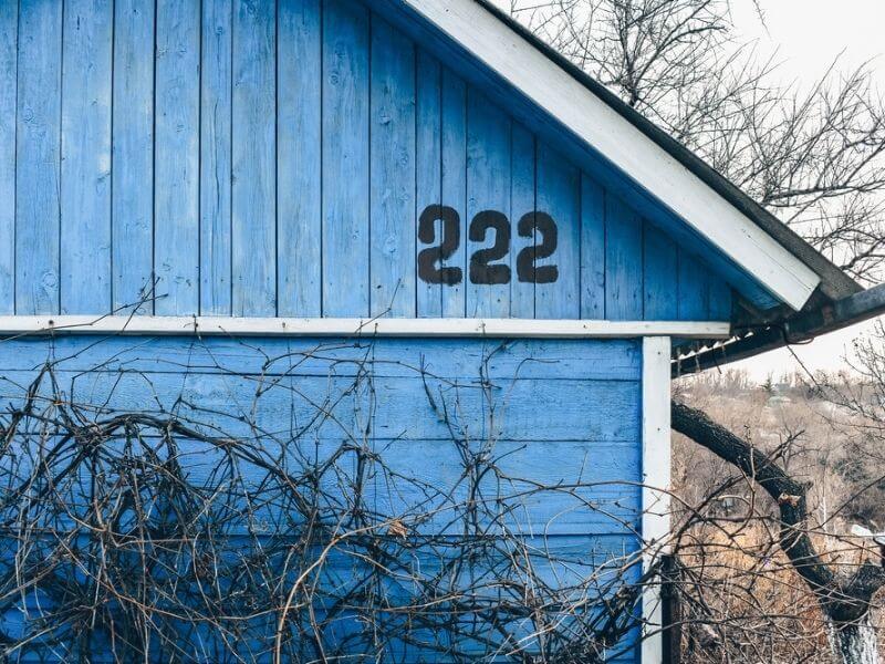 The number 222 written on the side of a blue house. 